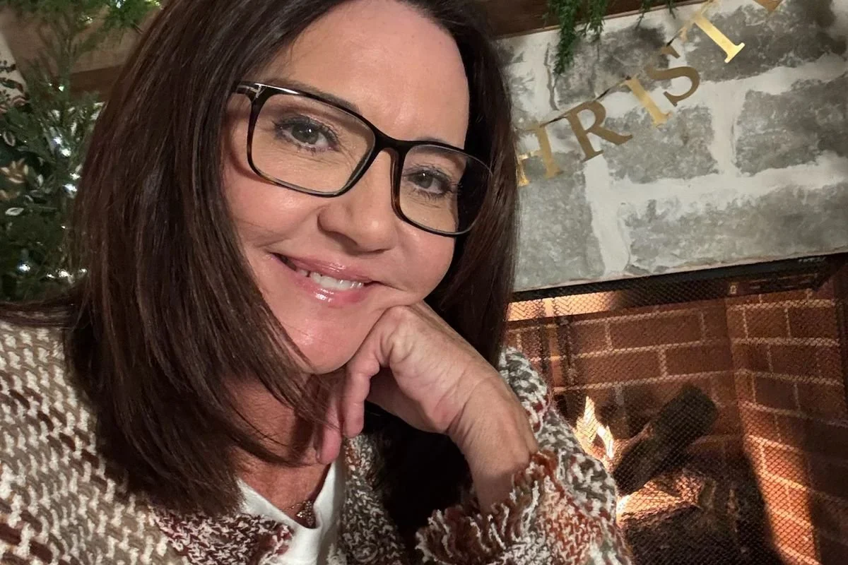Chantell Cooley smiling by a lit fireplace at Christmas, after learning to take the risk before seeing the whole picture