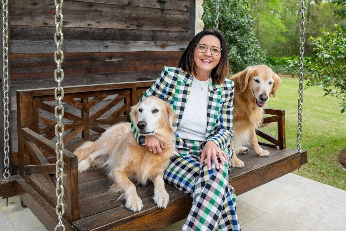 Chantell Cooley on a porch swing with her two golden retrievers, enjoying the seasons of life